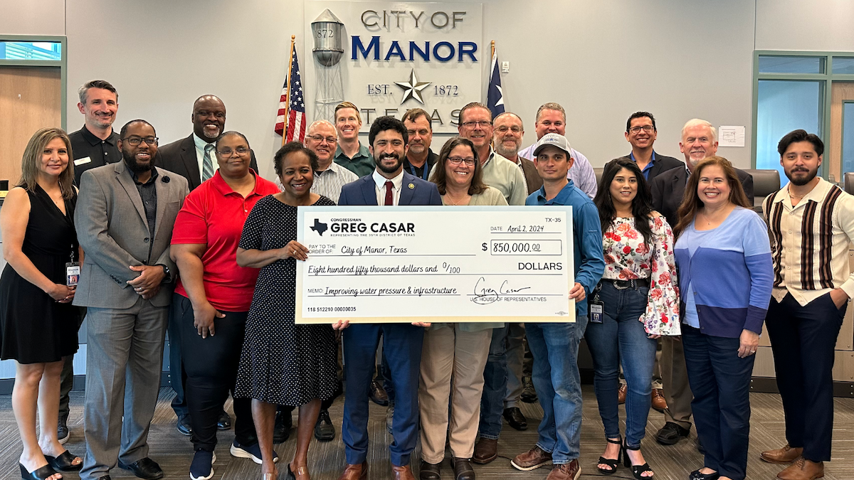 Congressman Casar poses with a check with Manor leaders at Manor City Hall
