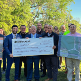 Congressman Greg Casar poses with a large check with Austin leaders in a park